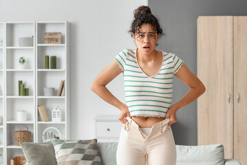 Young African-American woman in tight pants at home. Diet concept