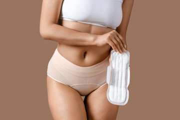 Young woman in menstrual panties with pad on brown background, closeup