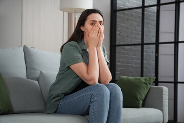 Depressed young woman sitting on sofa at home