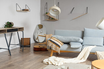 Interior of messy living room with sofa, shelves and broken mirror