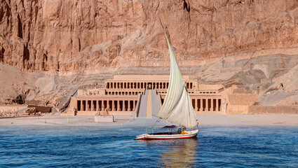 Beautiful Nile scenery with traditional Felluca sailing boat in the Nile Hatshepsut Temple at...