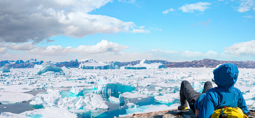 Environmental Concept - A Man Hiker looking at melting glacier - Melting of a iceberg and pouring...