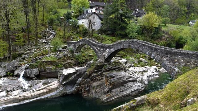 Famous bridge in between forest verzasca, lavertezzo. bridge calls ponte dei salti. You see the beautiful clear green water with a little waterfall. the stones and rocks are unique.