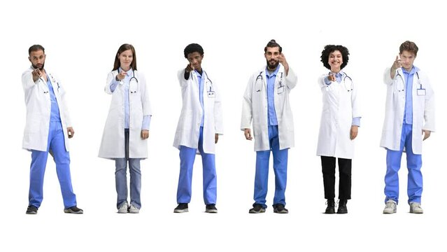A group of doctors, in full height, on a white background, points forward