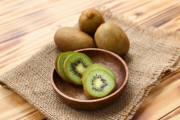 Bowl with slices of fresh kiwi on wooden background