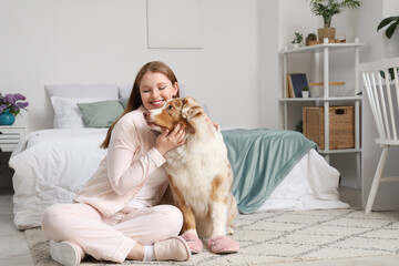 Young woman and cute Australian Shepherd dog with slippers at home