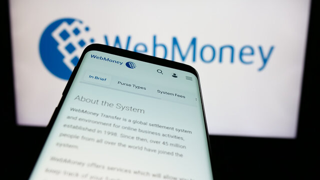 Stuttgart, Germany - 05-03-2024: Mobile phone with website of Russian online payment company WebMoney Transfer in front of business logo. Focus on top-left of phone display.