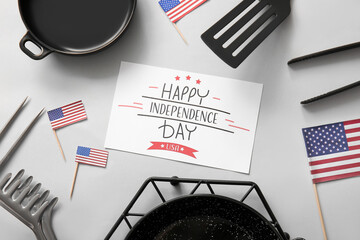 Composition with greeting card for Independence Day celebration, barbecue utensils and USA flags on...