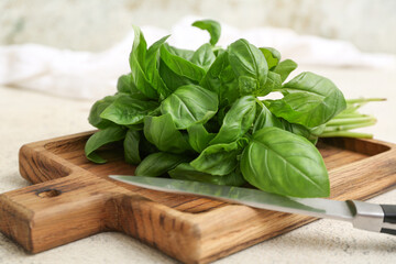 Wooden board with fresh green basil leaves on white background
