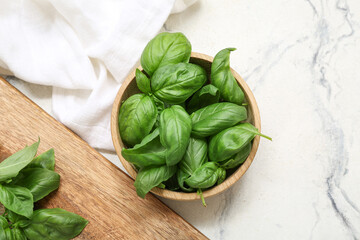 Wooden bowl and board with fresh green basil leaves on white background