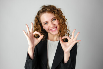 Young Woman Giving Ok Sign on gray background