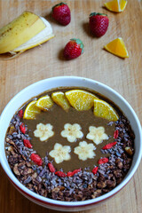 Healthy Raw Cacao chocolate smoothie bowl topping with cacao nibs and cacao granola goji berry banana and orange 