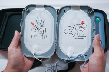 Automatic external defibrillator. Portable defibrillator on a wooden table. Defibrillator for medical care. Device for provision of emergency medical care. Automatic cardioverter with nursing manual