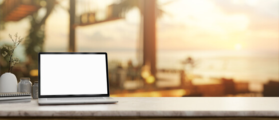 A laptop mockup on a tabletop, with a blurred background of a beachfront hotel lounge or restaurant.