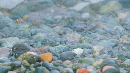 Colorful Sea Pebbles. Small Sea Foam Waves Breaking On A Pebble Beach. Close up.
