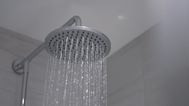 Shower head turns on, runs, then turns off. Close up static shot.