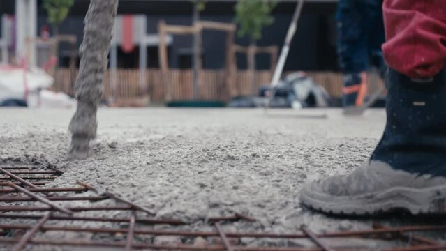 Construction worker pouring cement or concrete with pump tube