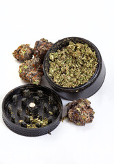 Cannabis strain with purple buds scattered around a black grinder. Isolated on white and loads of copy space

