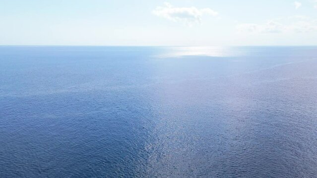 Light blue sky and horizon above current ripples of ocean water in Caribbean