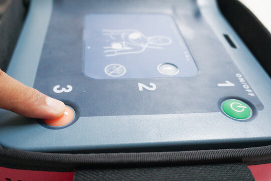 pressing the AED's shock button to deliver an electric shock to a heart attack patient