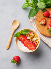 Natural yogurt with muesli and strawberries in a bowl on a blue background with fresh berries and...