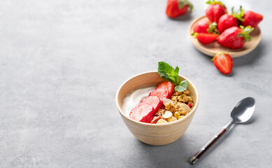 Natural greek yogurt with granola and strawberries in a bowl on a blue background with fresh...