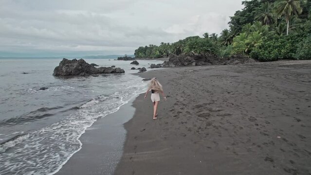 Blonde tourist walking alone on a desert tropical beach