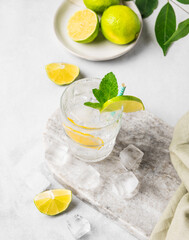 Mojito cocktail or tonic with lemon, lime, mint and ice on a marble board. Summer concept of...