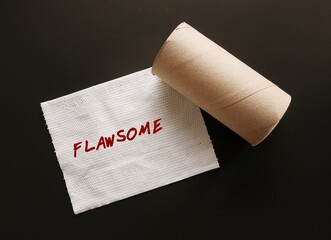 Toilet paper on black background with handwritten text FLAWSOME, refers to individual who embraces their flaws and loving themselves, knowing they are awesome, with all those flaws