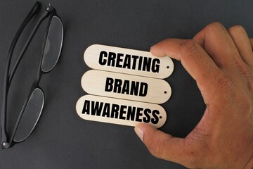 glasses and hand holding a stick with the words Creating brand awareness. The purposes of marketing...
