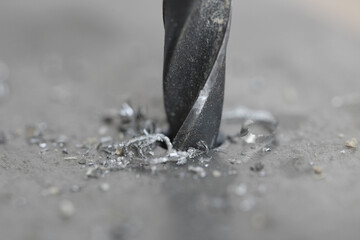 A metal drill bit makes holes in an iron sheet