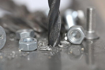 A metal drill bit makes holes in an iron sheet