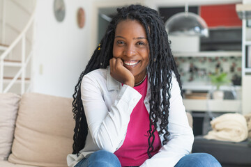 Laughing african american woman with dreadlocks indoors at living room