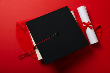 Graduate hat with diploma on red background.