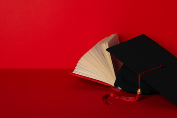 Graduate hat and books, on a red background.