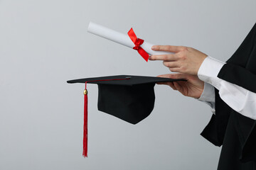 Diploma and hat of a university graduate, on a gray background.