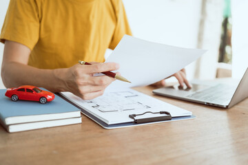 Close up man in yellow T-shirt working at desk. Automobile agreement and insurance documents. Legal...
