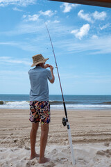 Man putting bait on his hook on the beach near Double Island Point. Ocean and waves at Teewah Beach. Queensland, Australia