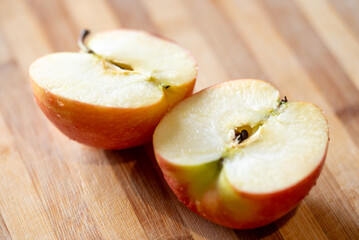 Close up of red apple cut into two halves, laying on the table. Ripe fruit, full of vitamins, ready to eat