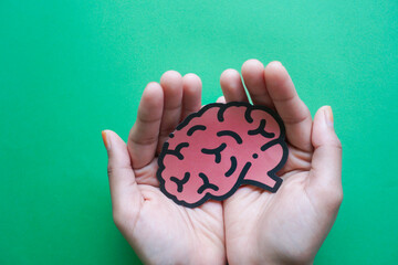 Woman hands holding human brain shape made from paper on light blue background. Awareness of...