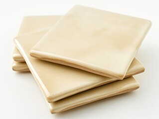 A neat stack of elegant beige ceramic tiles on a white background, suggesting home improvement and interior design.