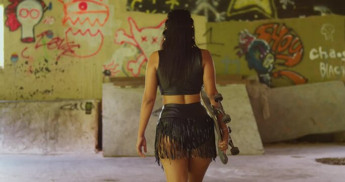 Dressed in a mini skirt, a Hispanic girl fearlessly conquers the ramps and rails of the indoor skatepark with her skateboard.