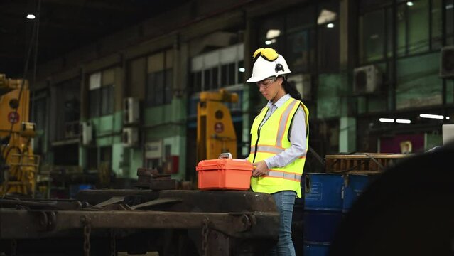 Portrait of railway technician worker in safety vest and helmet working with blueprint at train repair station
