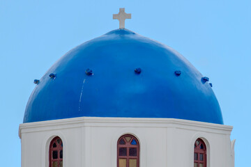 Santorini, Greece, May 5, 2024. Orthodox cross on a blue dome with blue sky