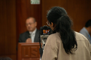 Student filming conference speakers, capturing knowledge in digital frames.