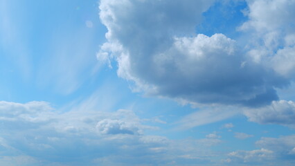 Sky with several layers of clouds moving in different directions. Sun rays at sunshine day. Time lapse.