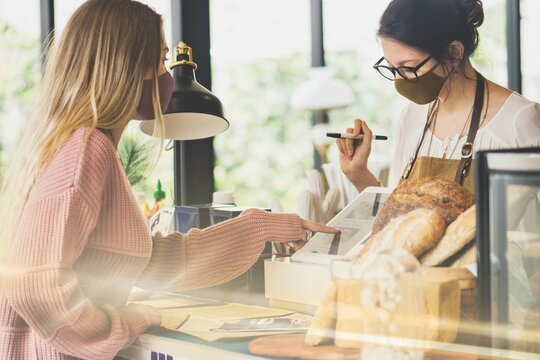 Woman wearing mask ordering food in a cafe restaurant covid 19