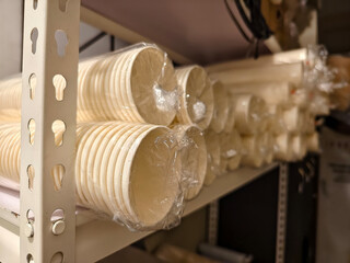 Close-up view of multiple stacks of disposable paper cups, each bundle wrapped in transparent...