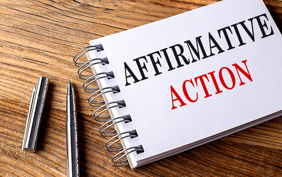 AFFIRMATIVE ACTION text on notebook with pen on the wooden background 