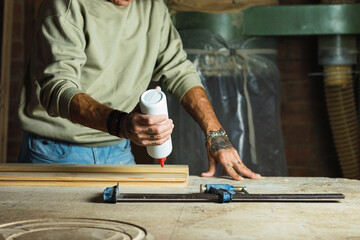 Carpenter putting glue on wooden boards